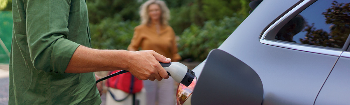 Couple charging their electric vehicle at home