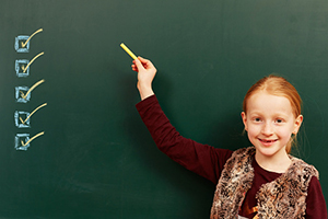 Kid with checklist on chalkboard